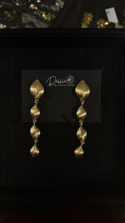 Gold cascading leaf earrings with textured metallic finish on black branded card