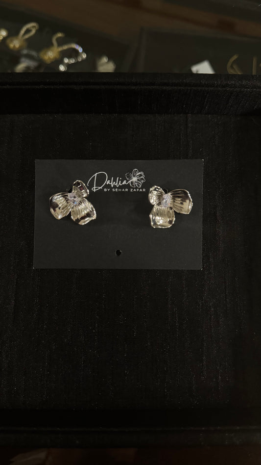 Gold three-petal floral earrings with central gem detail on black branded card