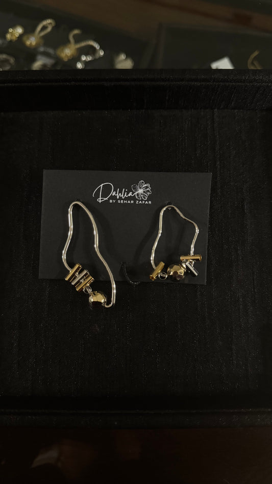 Abstract wire earrings with gold-toned beads and sculptural form on black branded card