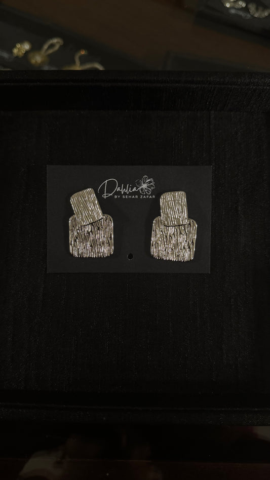 Gold textured rectangle earrings with geometric drop design on black branded card