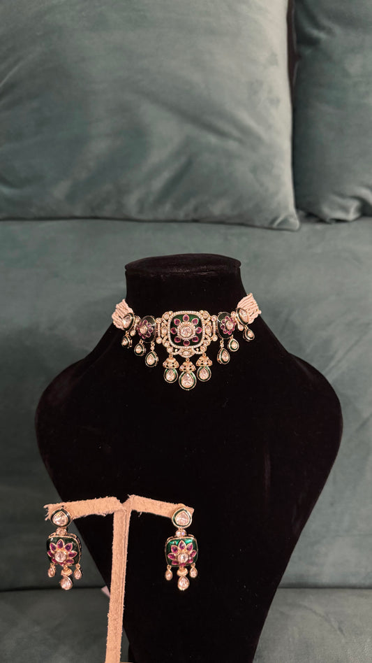 Traditional choker necklace sets with floral motifs, teardrop accents, and multicolor stones on black velvet stand
