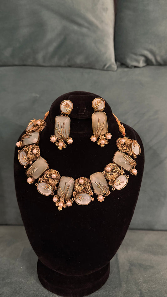 Traditional necklace sets with floral-embedded rectangular stones and pearl clusters on black velvet bust