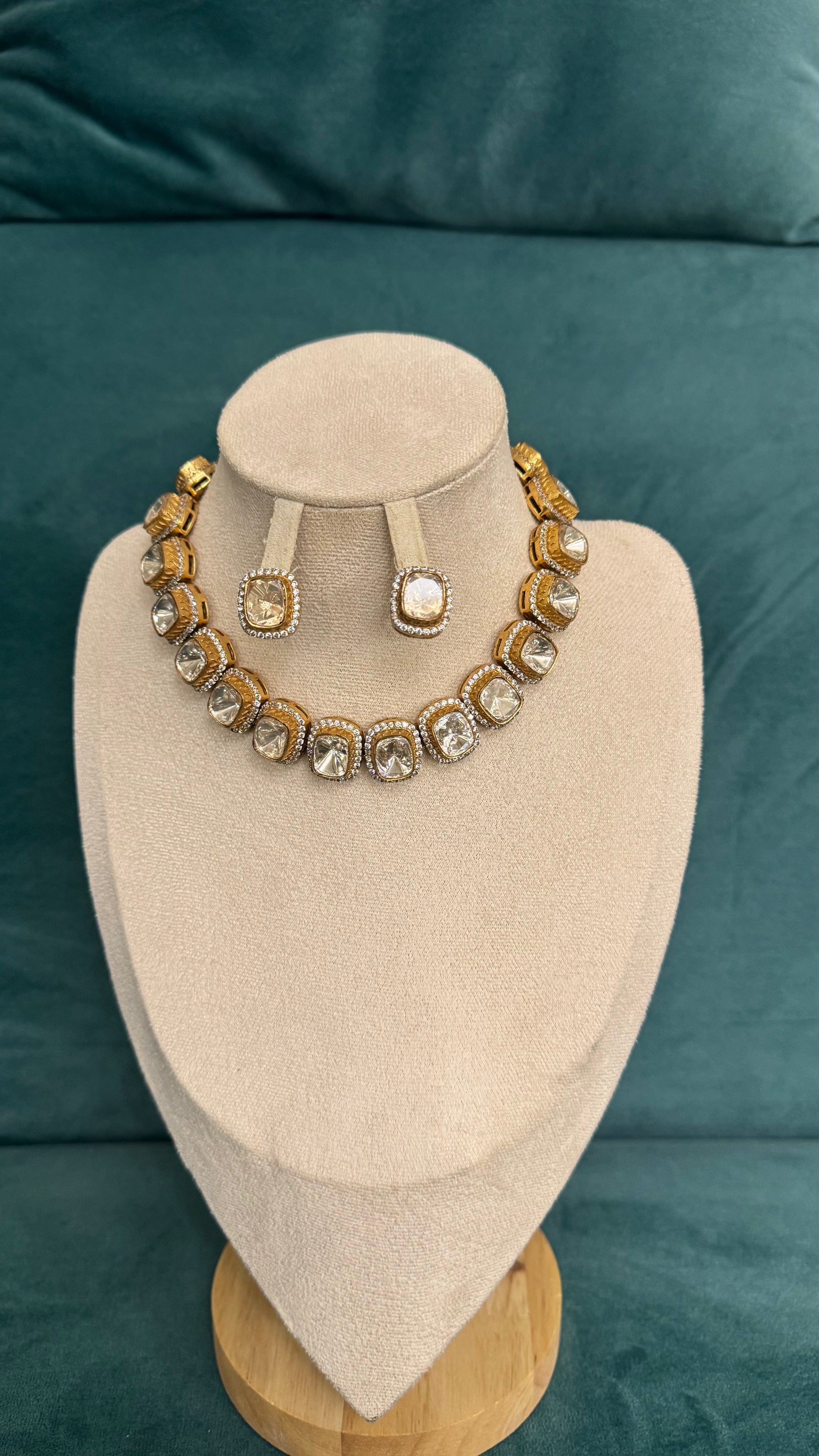 Luxury necklace sets with gold segments, diamond-like stones, and ornate detailing on beige velvet bust