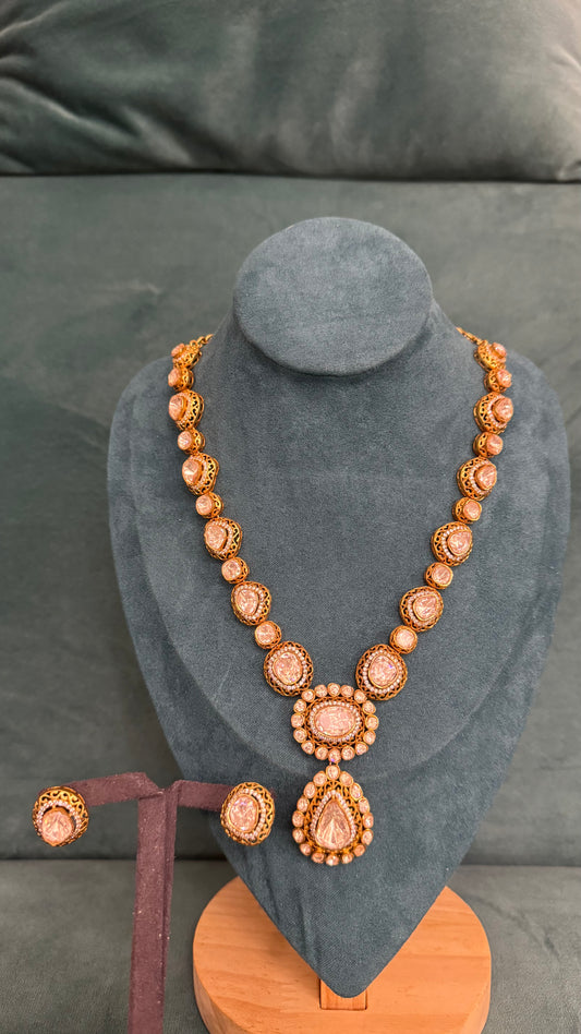 Traditional necklace sets with teardrop pendant, gold craftsmanship, and central stone accents on dark velvet bust