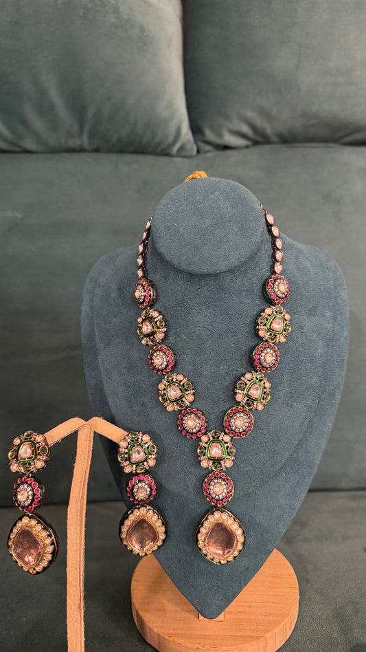 Traditional necklace sets with floral motifs and teardrop pendants on blue velvet bust