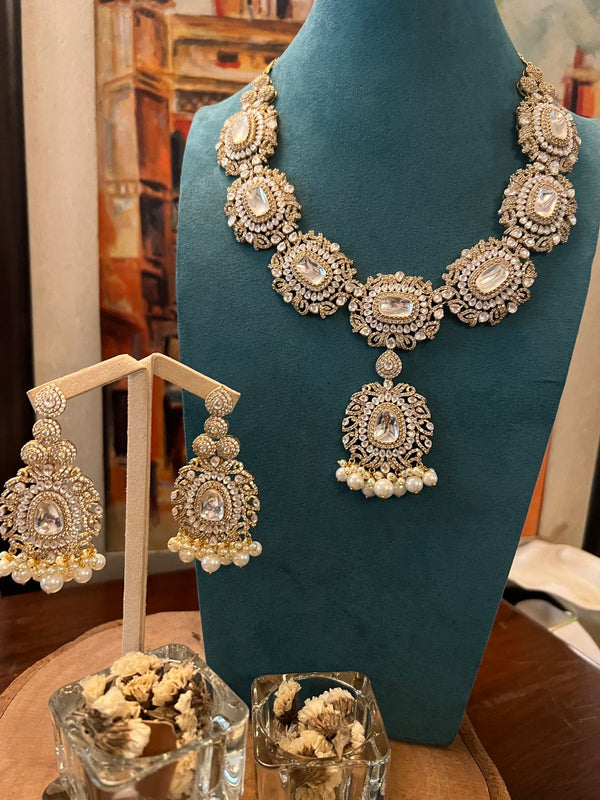 Kundan necklace with pearl drop pendants and matching earrings displayed on a teal stand.