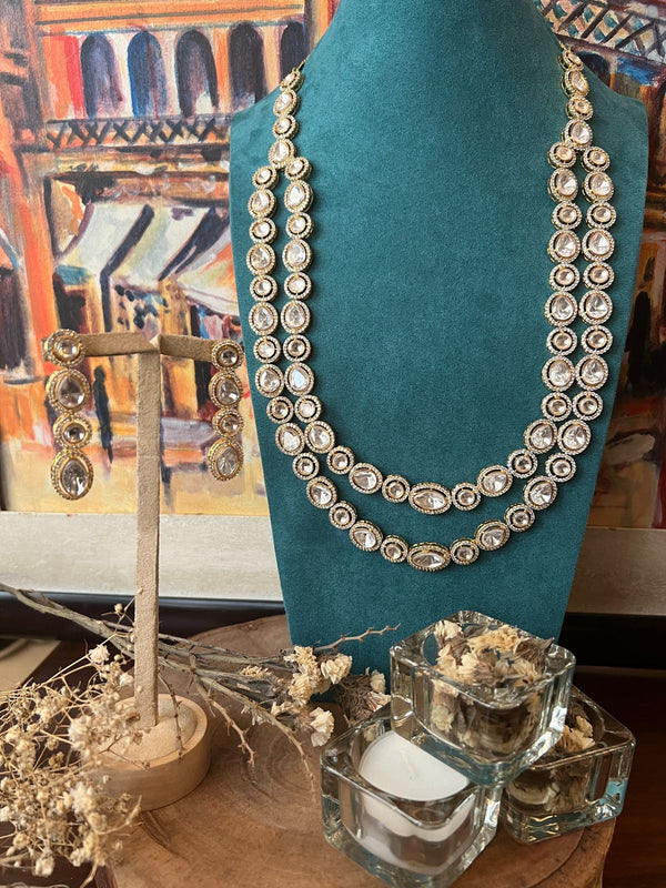 Double-layer Kundan necklace made with 24 karat gold plated materials displayed on a teal stand.