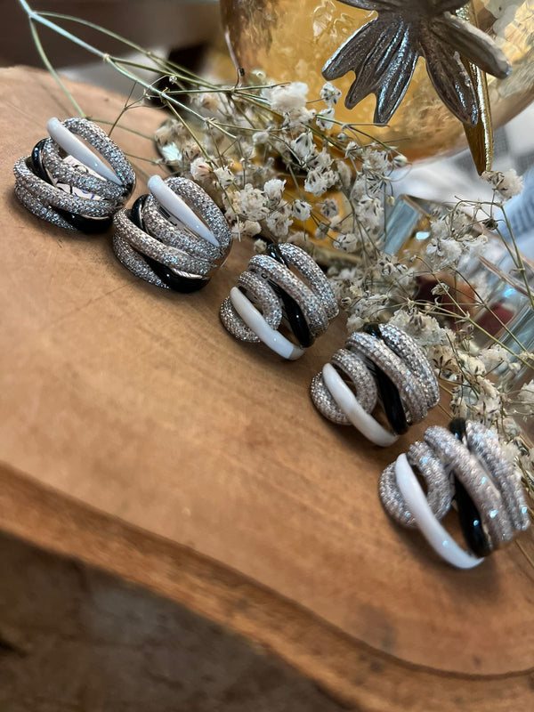 A collection of cocktail rings with a geometric shape, featuring black and white colors, adorned with silver and gold details.