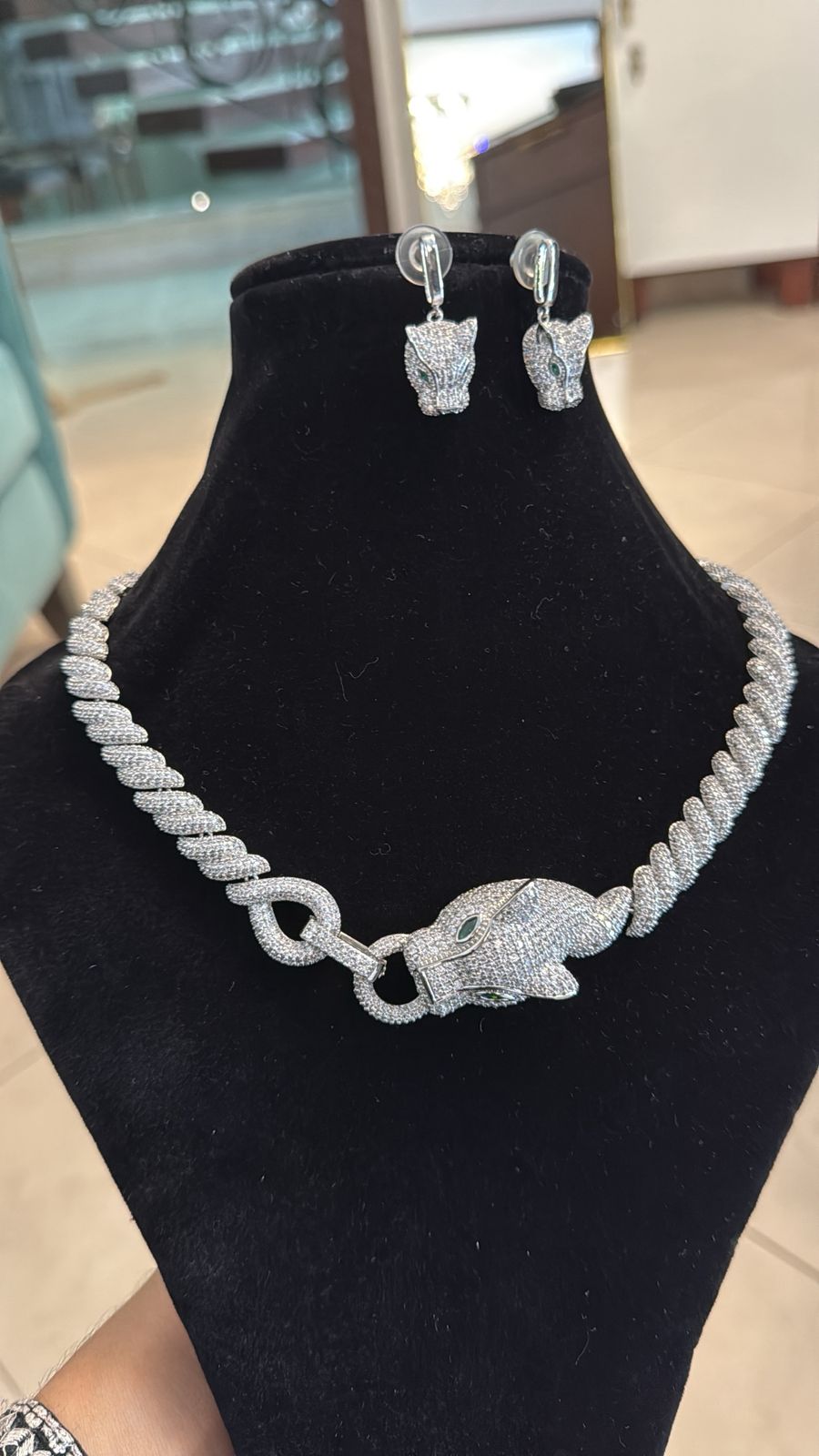 Silver elephant necklace and earrings on a black stand with a blurred background