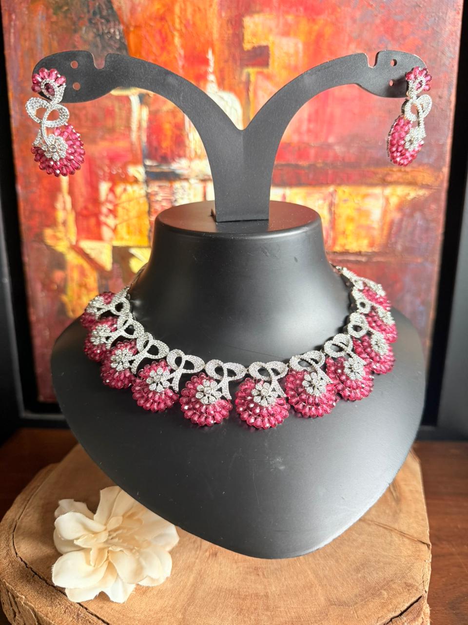Necklace and earrings on a black stand with a colorful abstract background