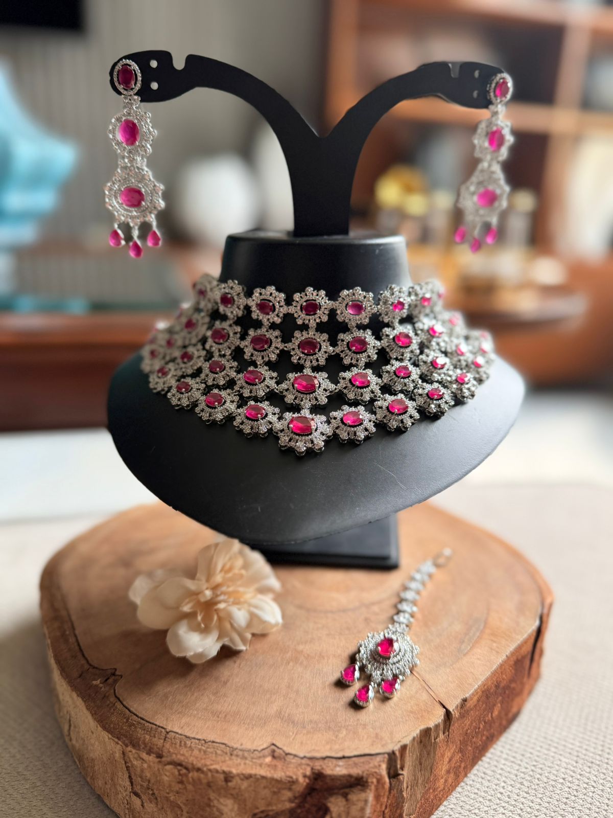 Jewelry set including necklace, earrings, and bracelet on a wooden stand with a blurred background.