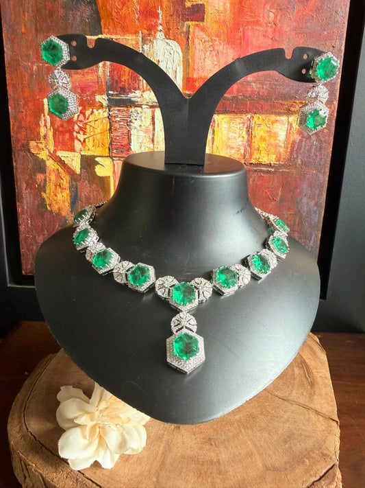 Emerald and diamond necklace on a black stand with a colorful abstract painting in the background.