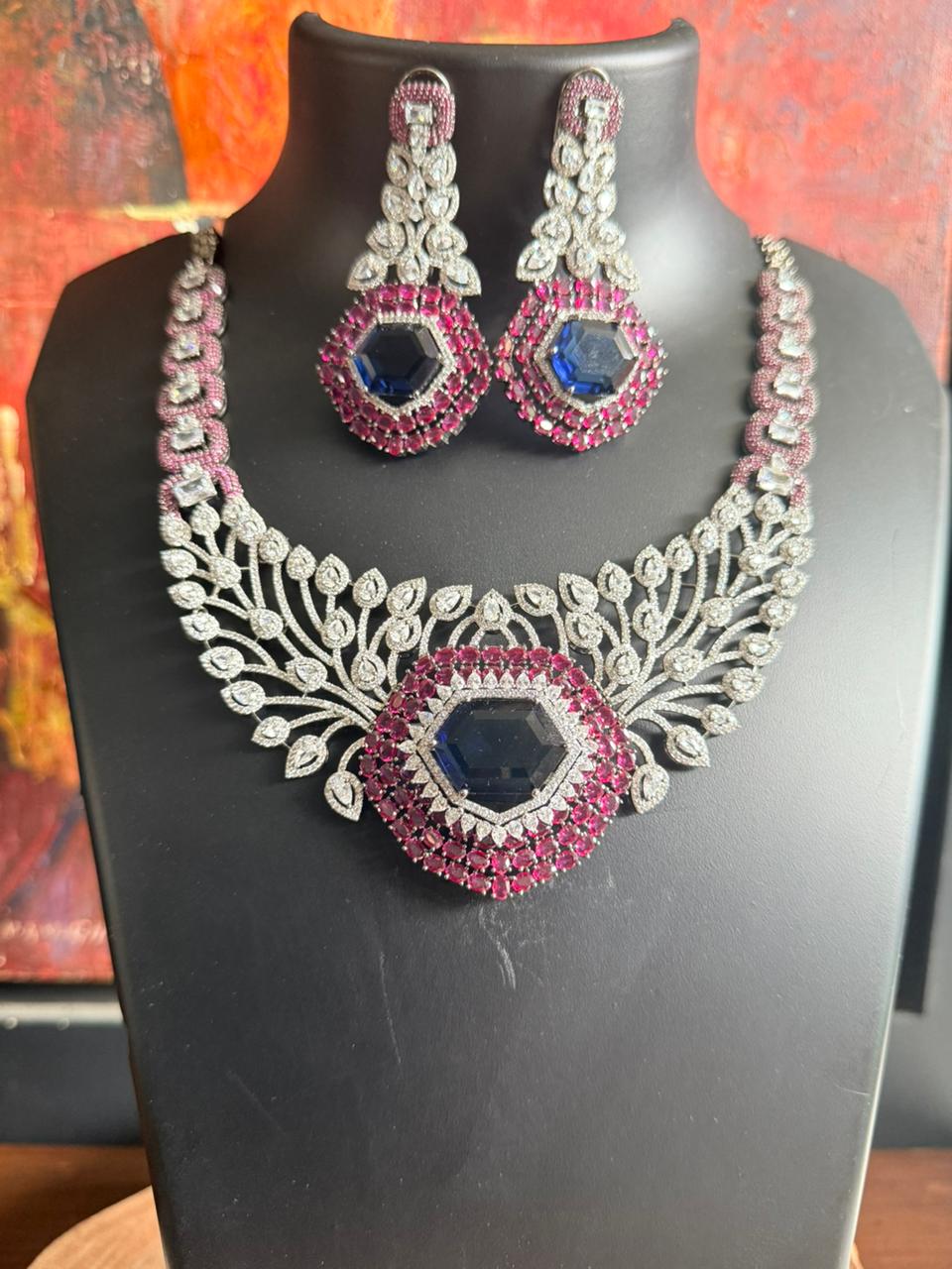 Jewelry set with necklace and earrings on a mannequin bust against a colorful background