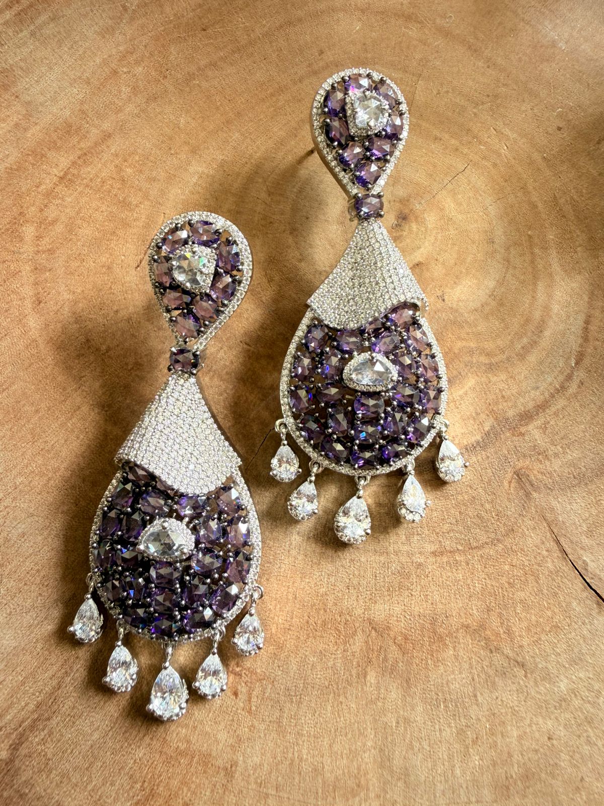 Pair of purple and silver earrings on a wooden surface