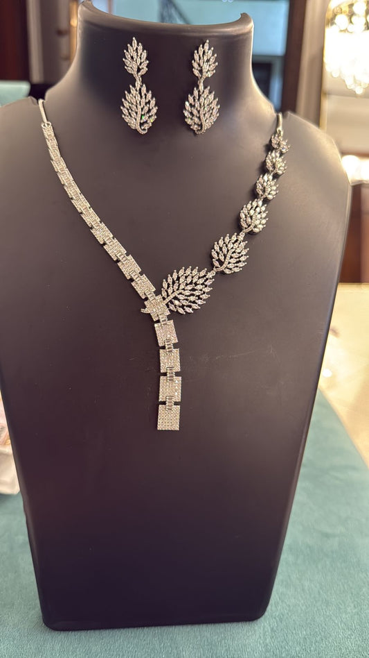 Silver necklace and earrings on a mannequin bust with a blurred background