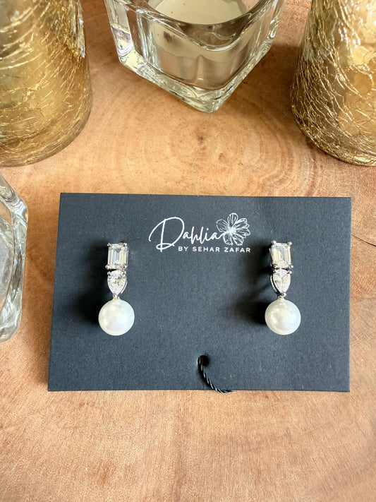 Pair of earrings on a display card with 'Dahlia by Sehar Zafar' branding on a wooden surface.