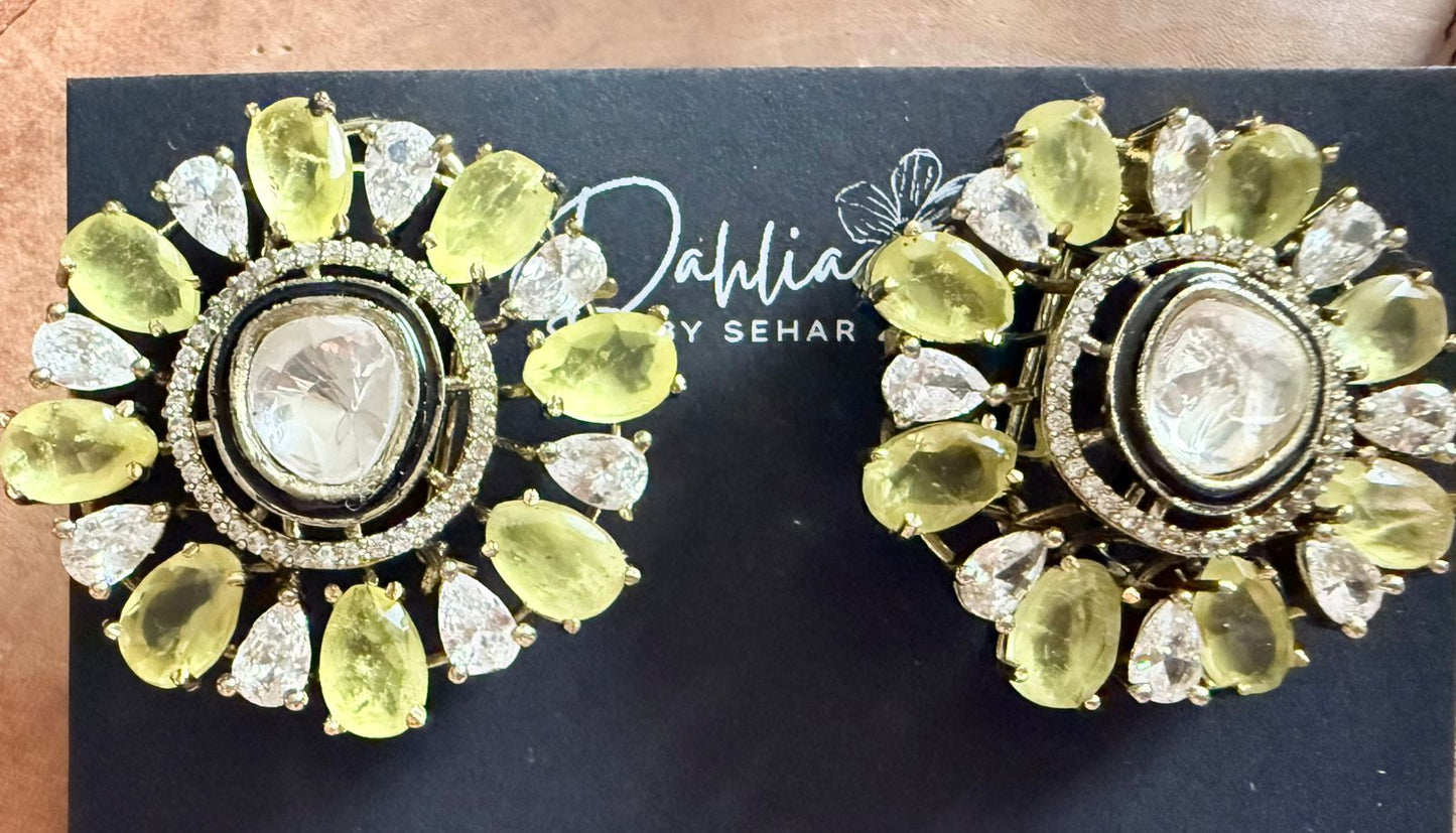 Pair of ornate earrings with green and gold stones on a black background with 'Dahlia by Sehar' branding.