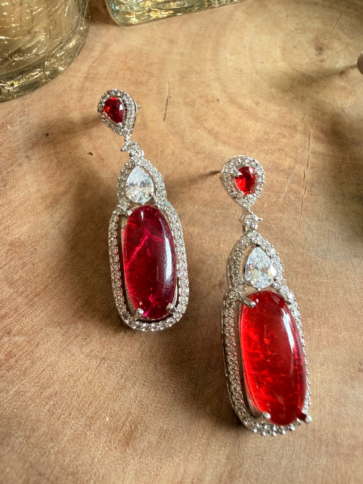 Red gemstone earrings with silver accents on a textured surface