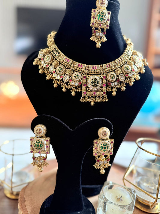 Gold necklace and earrings set on a black mannequin bust with blurred background