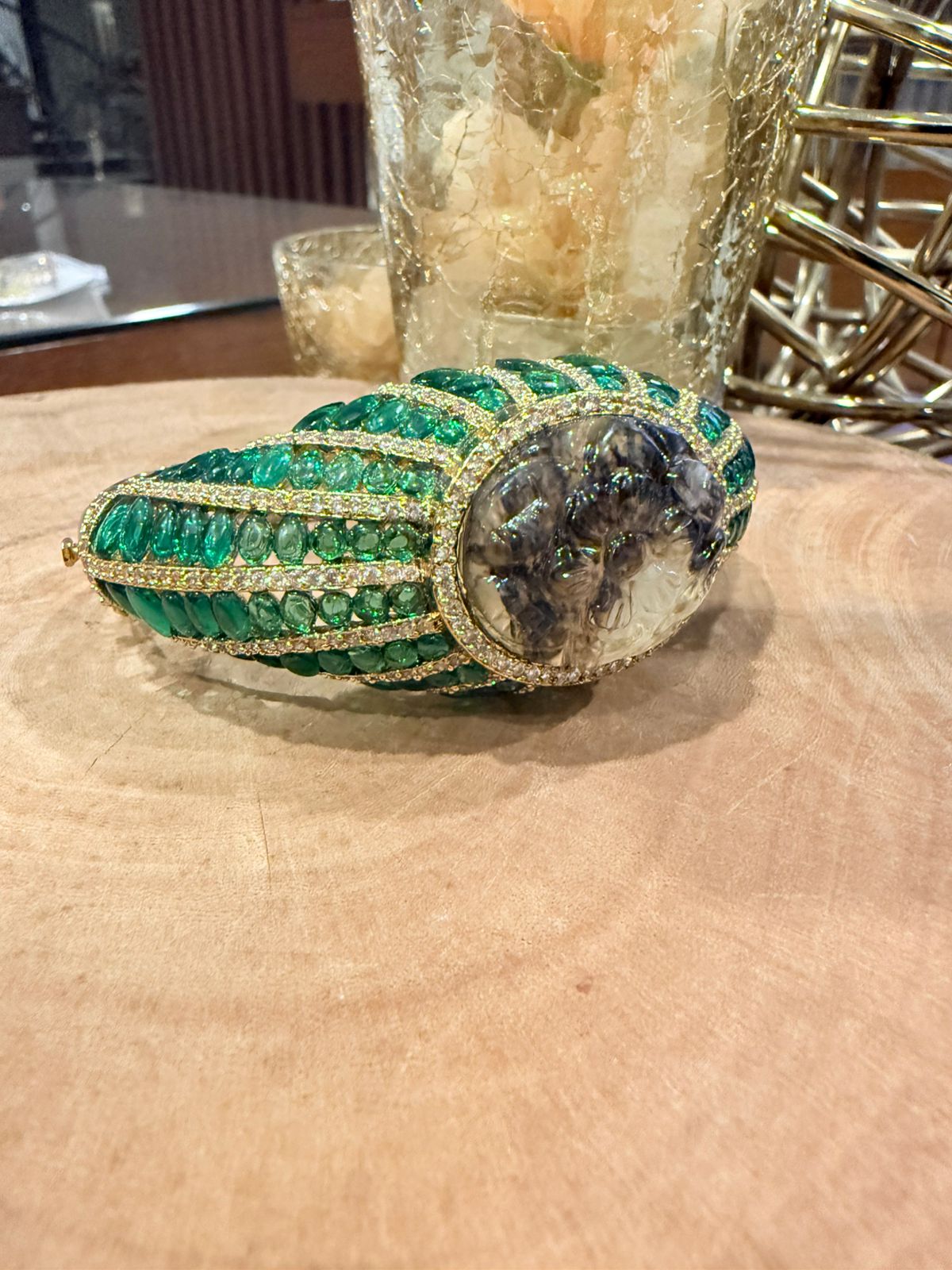 Green gemstone ring with a dark stone on a wooden surface