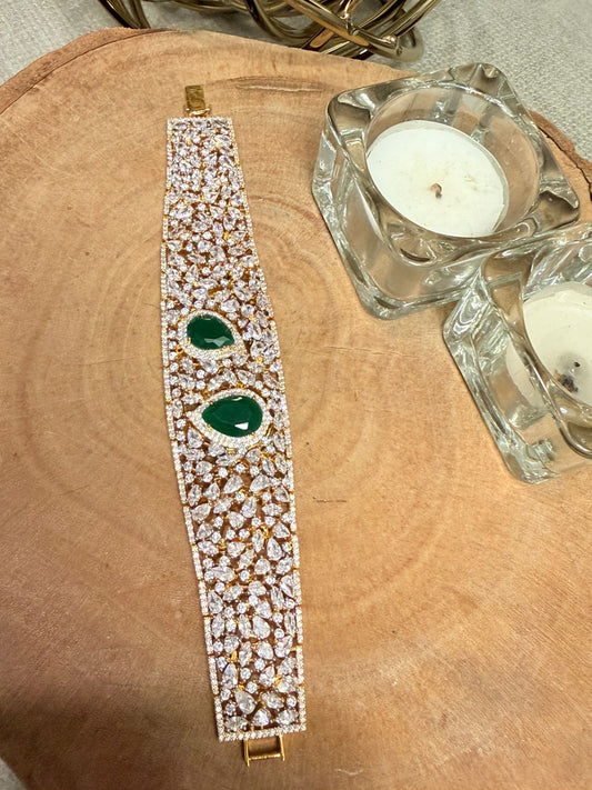 Decorative bracelet with green stones on a wooden surface with candles.