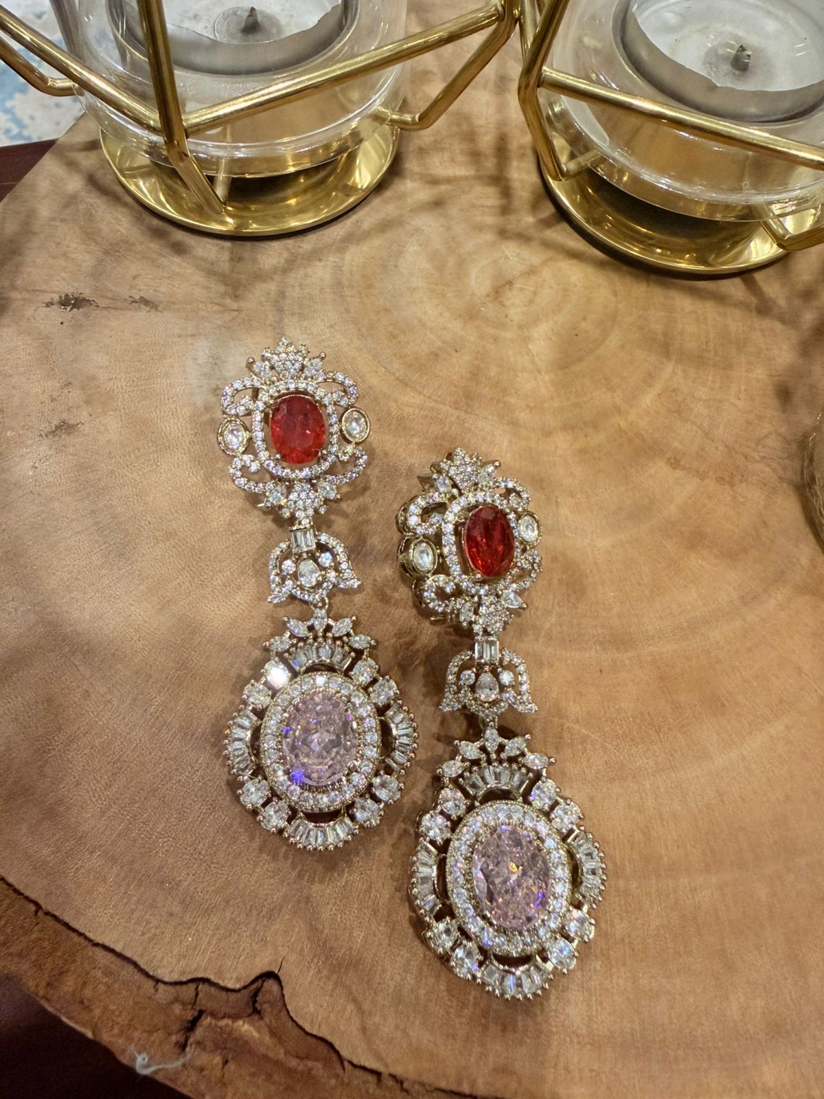 Pair of ornate earrings with gemstones on a wooden surface