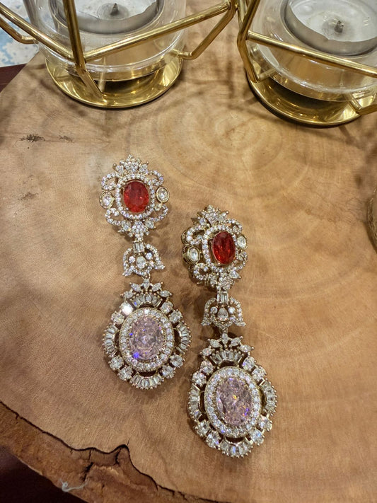 Pair of ornate earrings with gemstones on a wooden surface