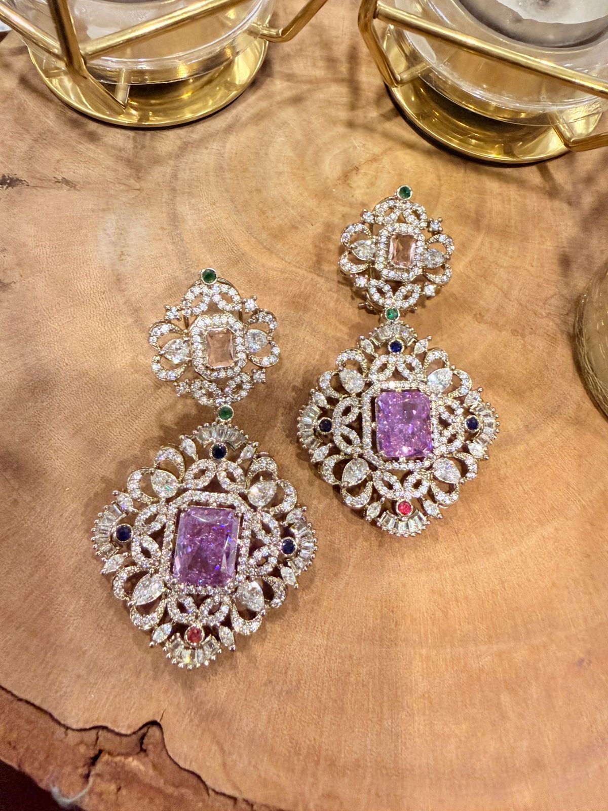 Ornate earrings with purple gemstones on a wooden surface