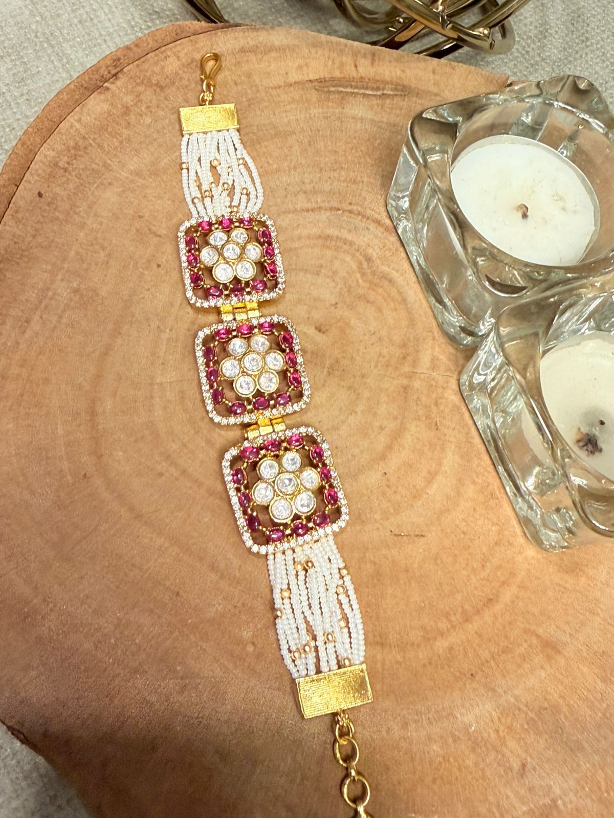 Decorative bracelet with pink and gold accents on a wooden surface
