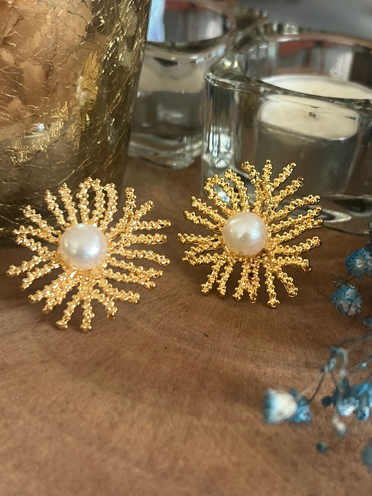 Gold earrings with pearl centers on a wooden surface