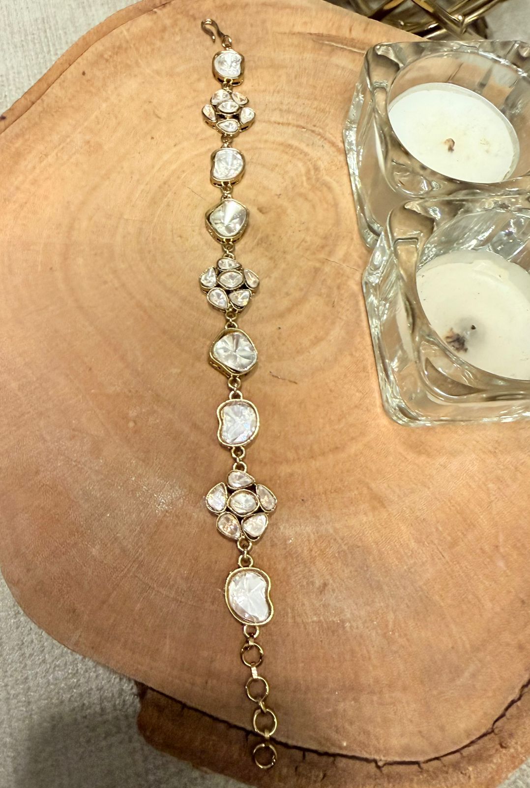 Gold bracelet with clear stones on a wooden surface