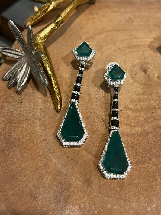 Pair of green gemstone earrings on a wooden surface