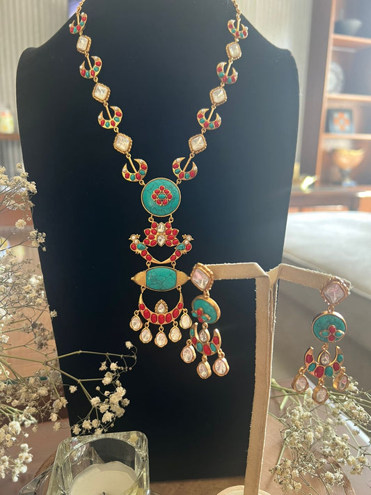 Ornate necklace with turquoise and red stones on a black stand.