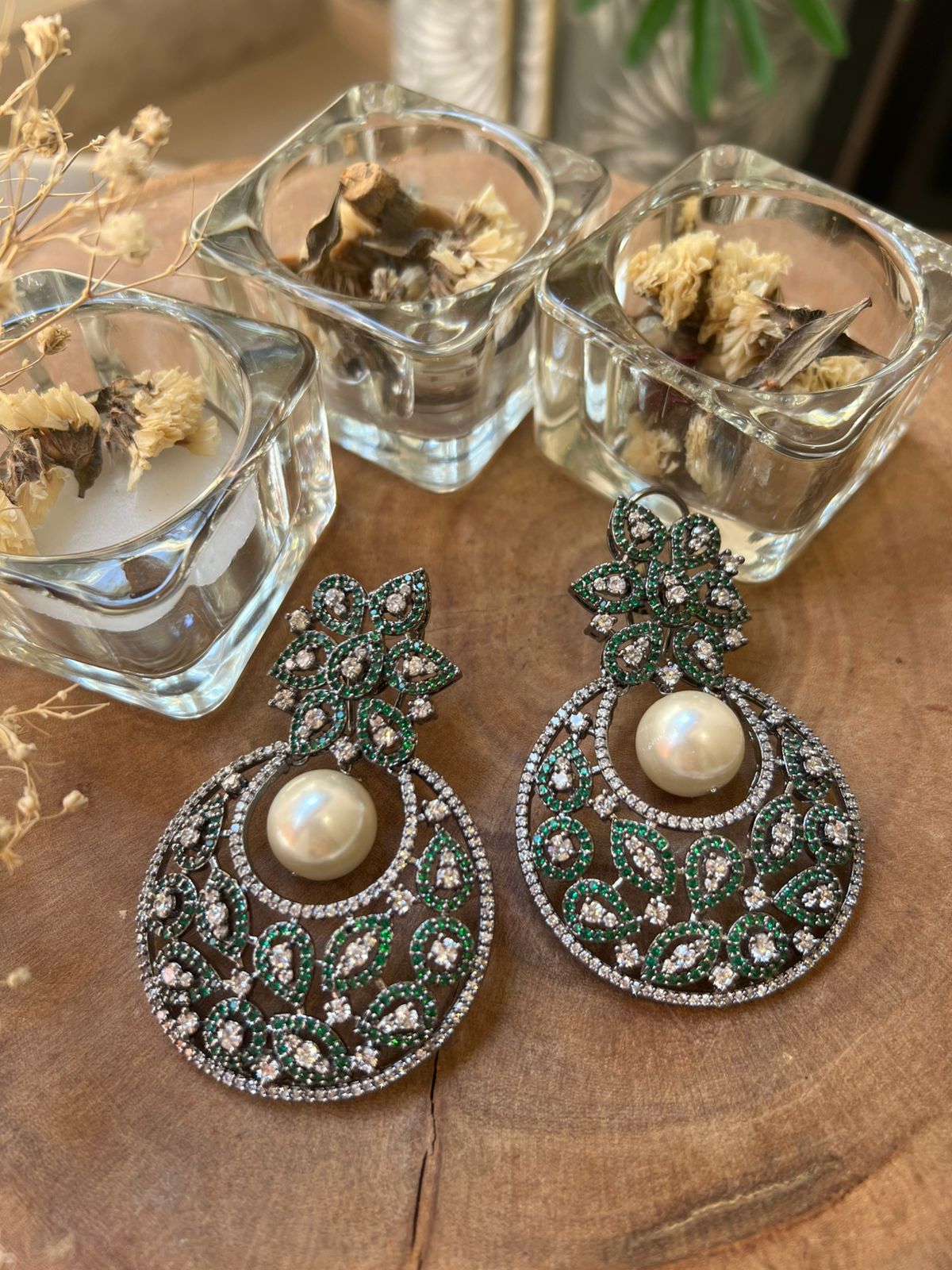 Ornate earrings with pearls on a wooden surface