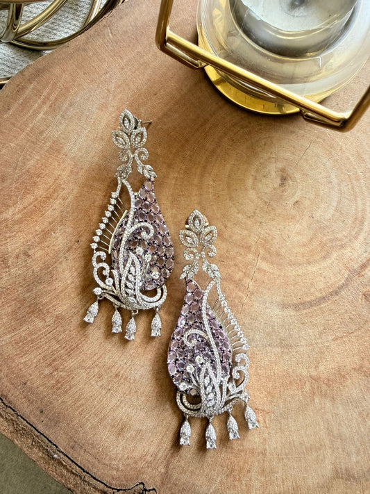 Ornate earrings with purple stones on a wooden surface