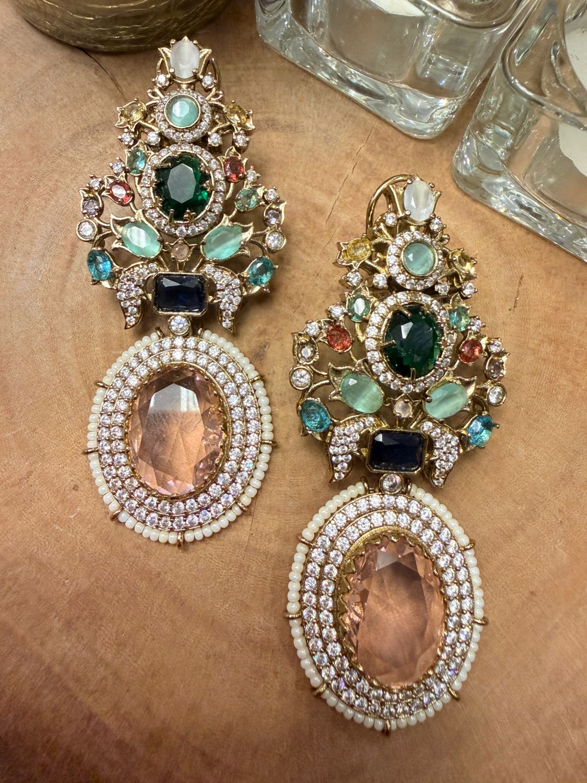 Ornate earrings with gemstones on a textured surface