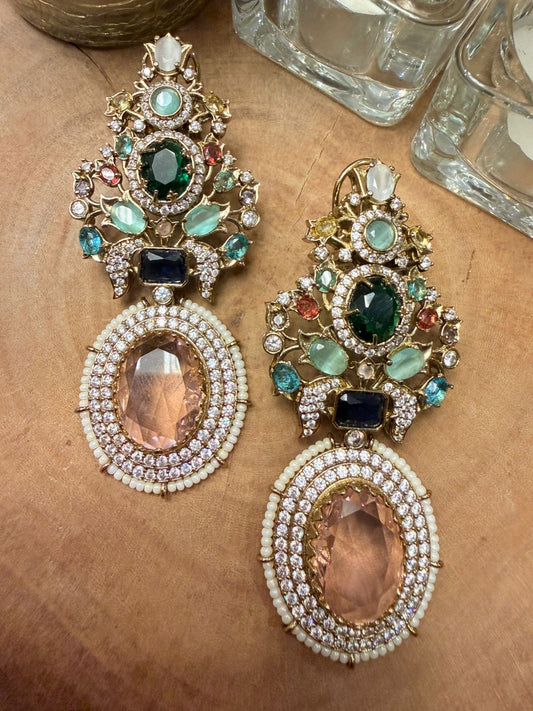 Ornate earrings with gemstones on a textured surface
