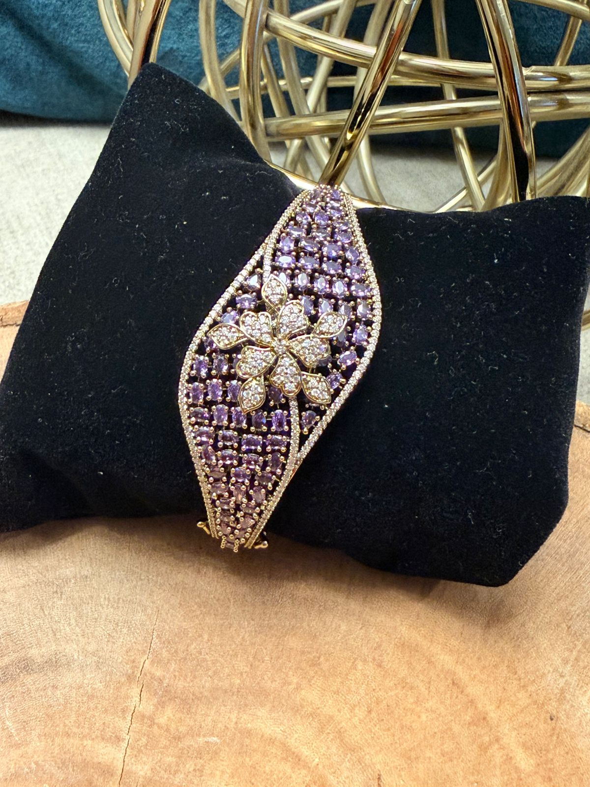 Decorative brooch with purple and gold design on a black cushion
