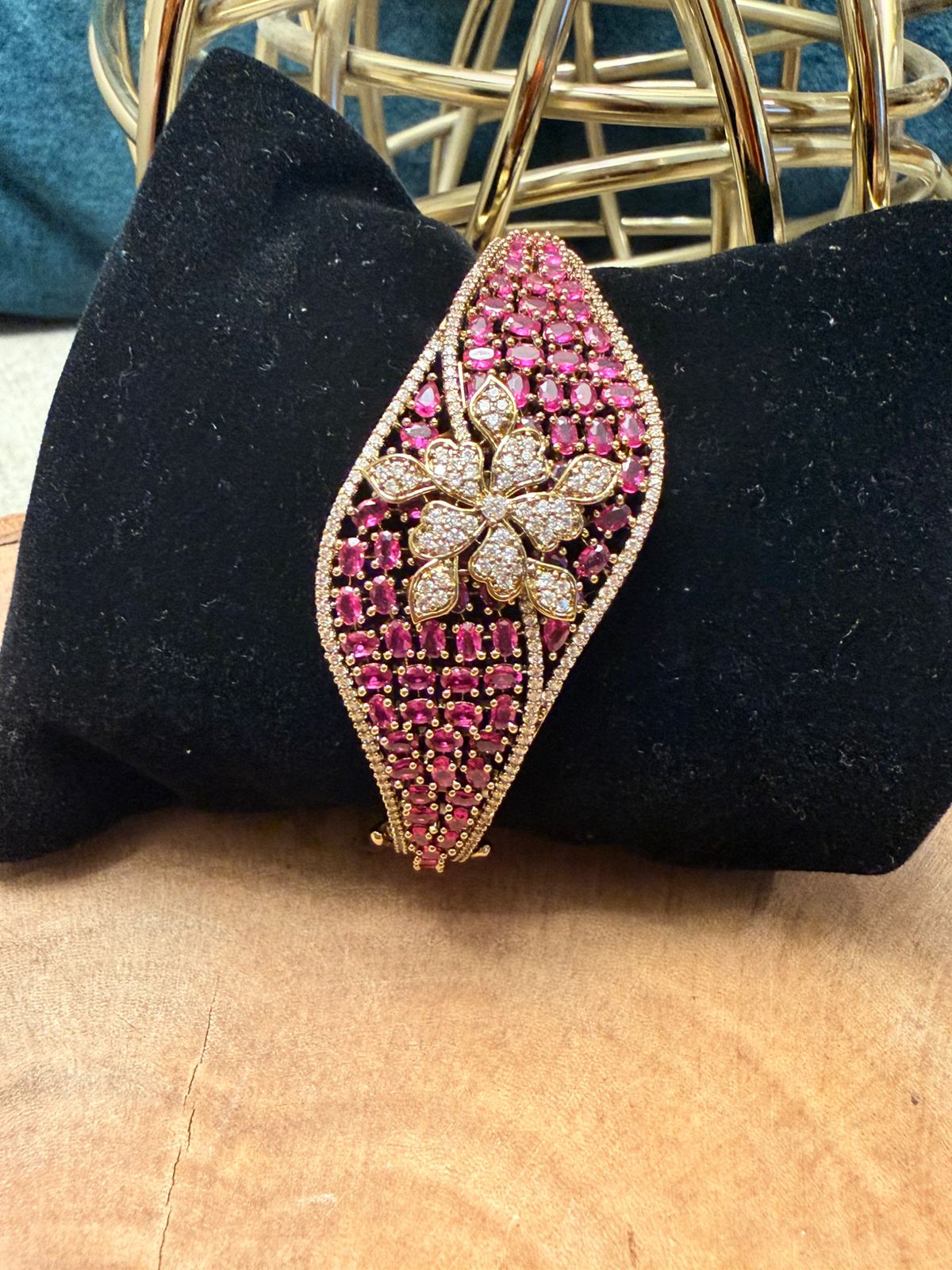Decorative brooch with pink gemstones and gold accents on a black cushion