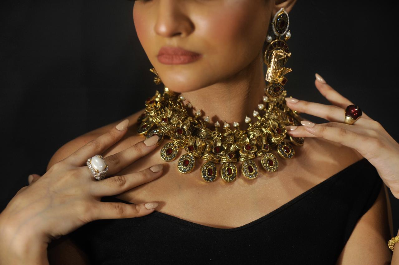 Woman wearing a gold necklace with intricate designs, close-up shot.