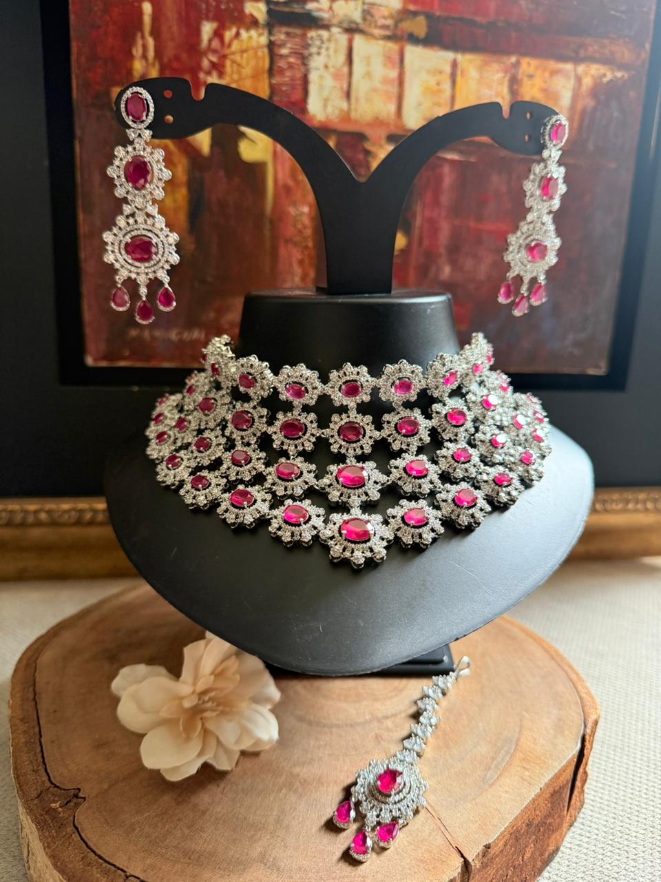 Jewelry set with necklace, earrings, and bracelet on a decorative stand.