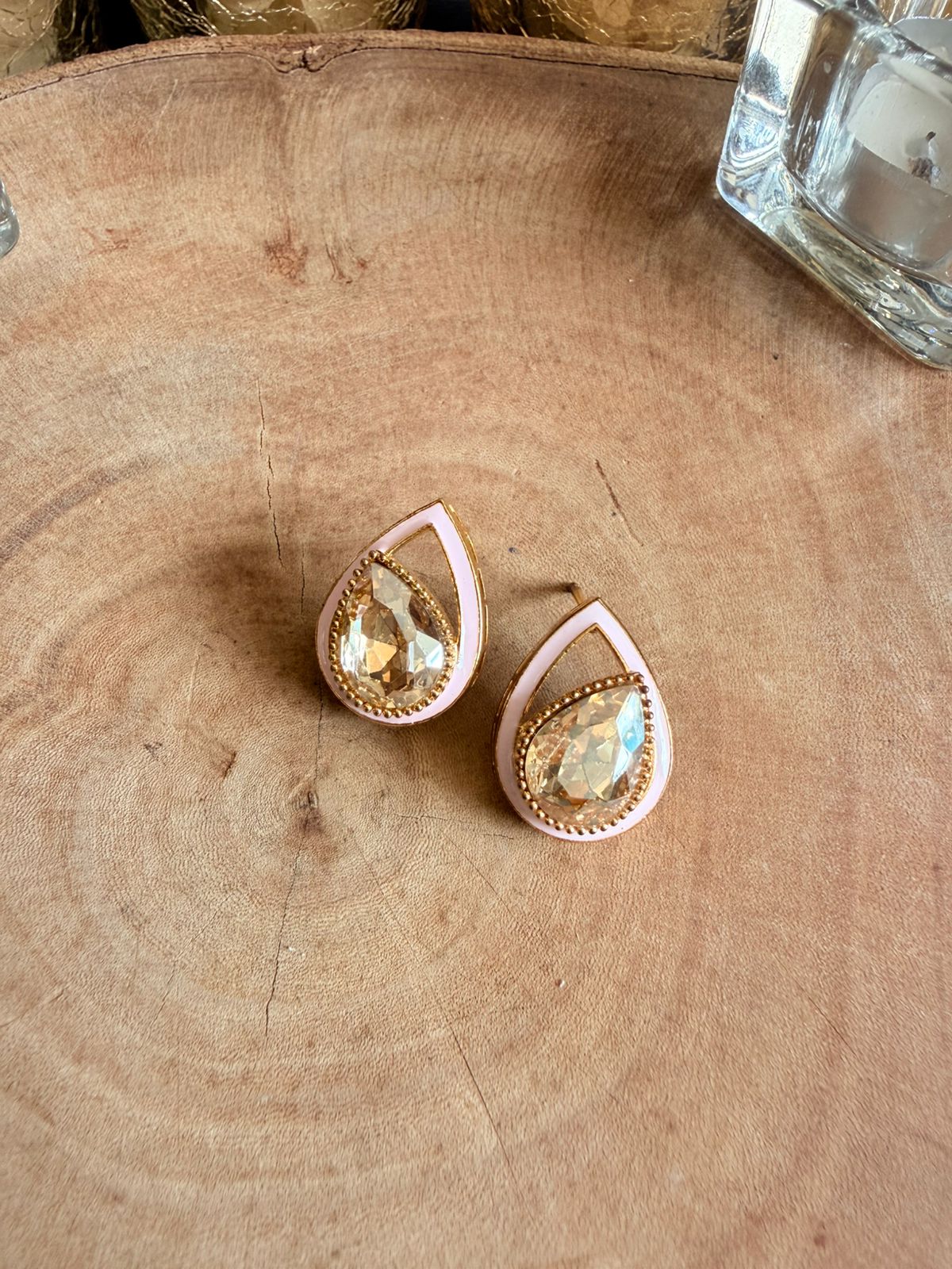 Teardrop-shaped earrings with pink and gold accents on a wooden surface