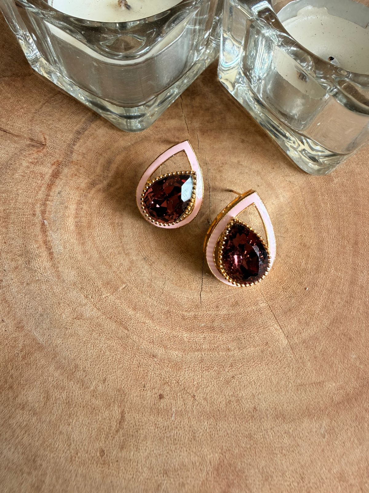 Teardrop-shaped earrings with rose gold accents on a wooden surface